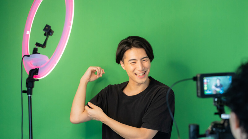 インフルエンサーの男性が、グリーンバックの前で撮影している風景の写真