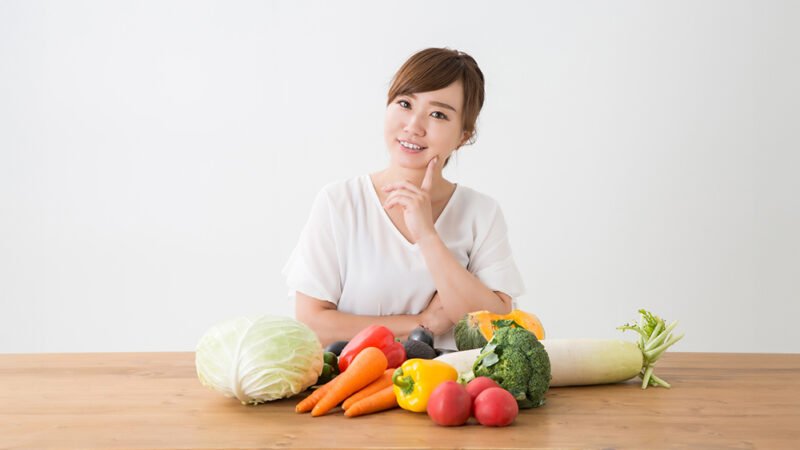 野菜を前に考えている女性の写真