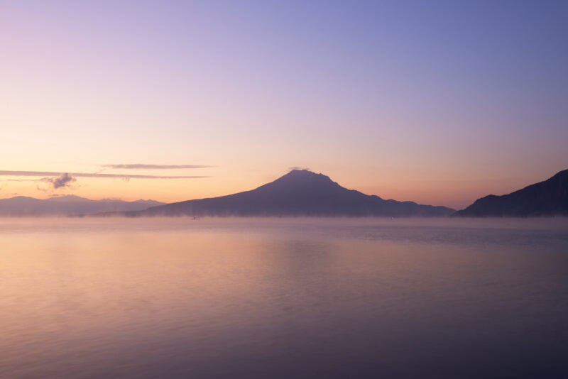 朝焼けを背景に水面に反射している山の写真