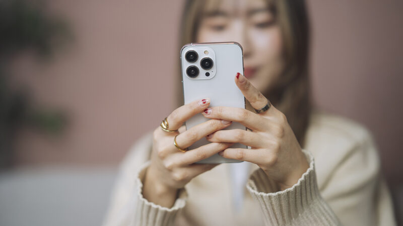 スマートフォンを手に持って、操作している女性の写真