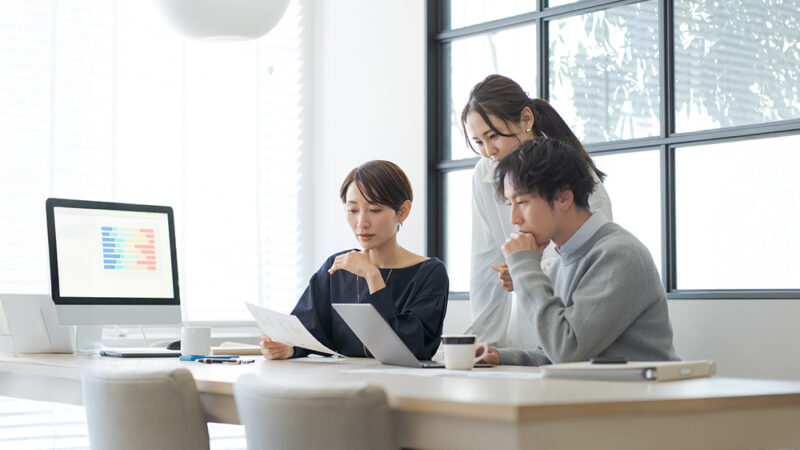 PCの前で打ち合わせをしている男女の写真