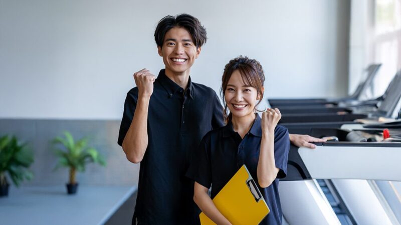 男女のジムトレーナーがガッツポーズしている写真