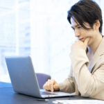 パソコンの画面を見ながら悩んでいる男性の写真