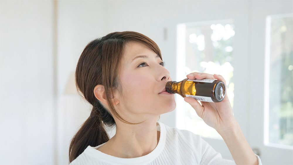 女性が茶色い瓶のドリンクを飲んでいる写真