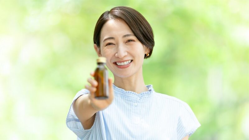 茶色い瓶の飲み物を掲げている女性