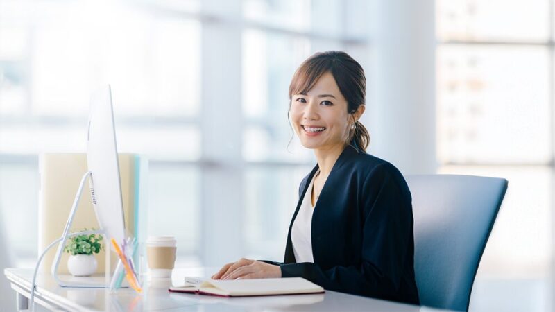 スーツの女性がパソコンの前で笑っている写真