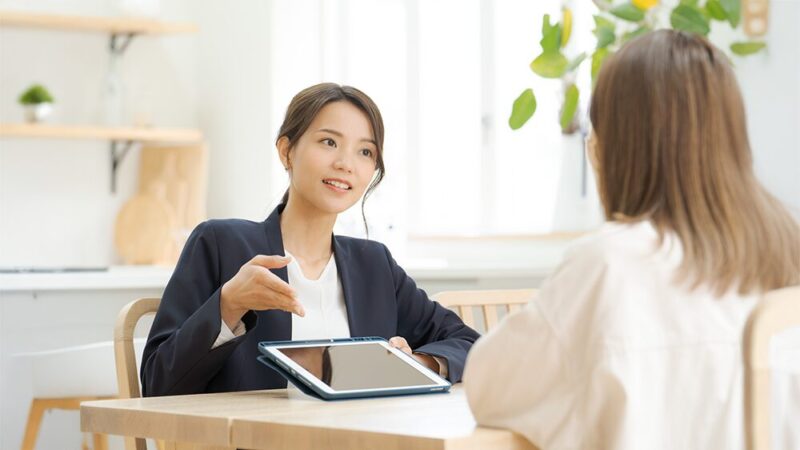 スーツの女性がタブレットを見せながら女性に説明している写真