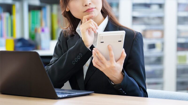 電卓を持った女性が悩んでいる写真