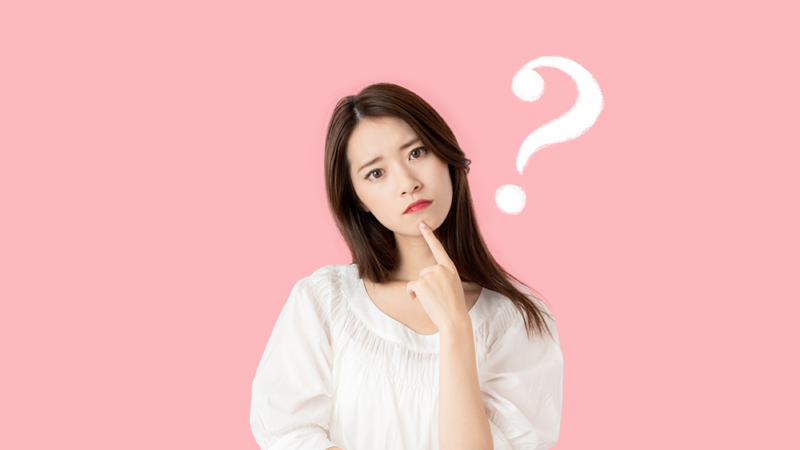 首をかしげている女性と「？」マークの写真