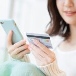 スマートフォンとクレジットカードを持っている女性の写真