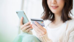 スマートフォンとクレジットカードを持っている女性の写真