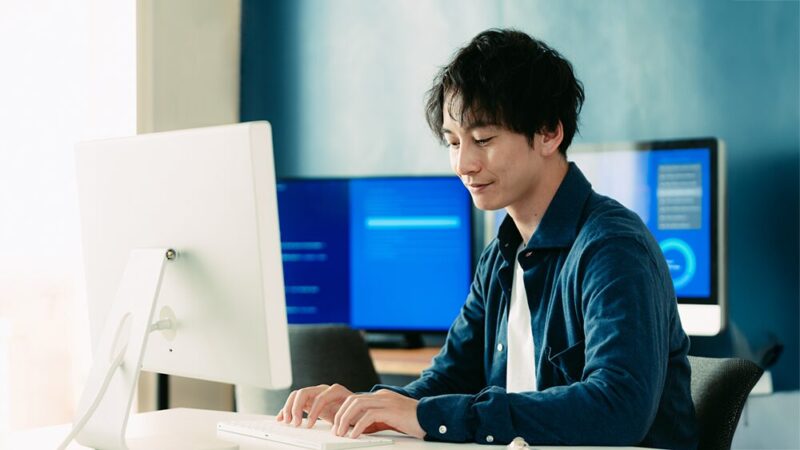 男性がパソコンのタイピングをしている写真