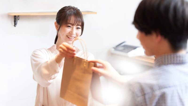 女性が紙袋を男性に渡している写真
