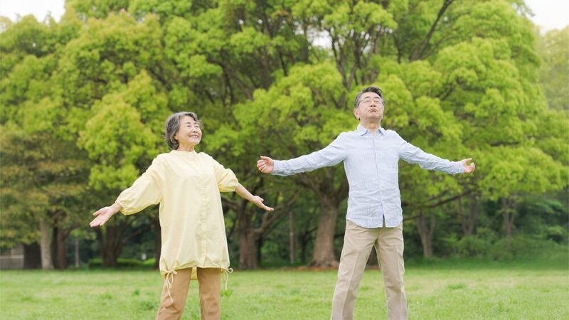 シニアの男女が公園で体操している写真