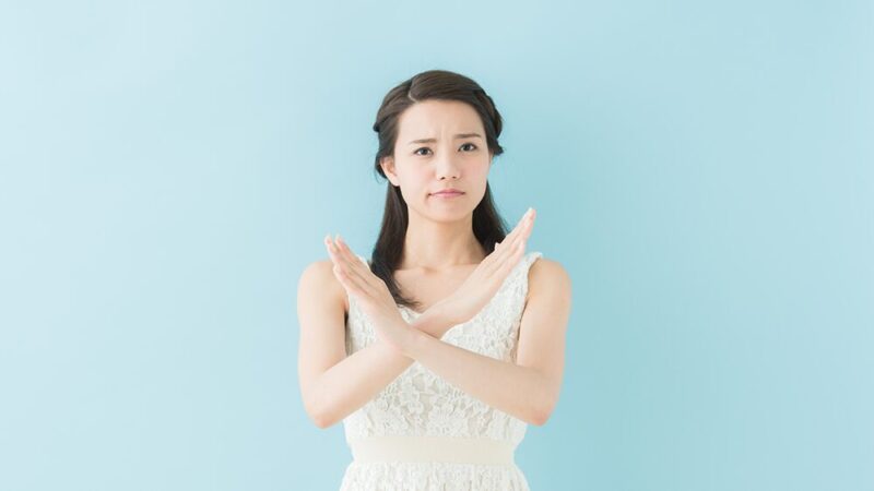 女性が腕で×を作っている写真