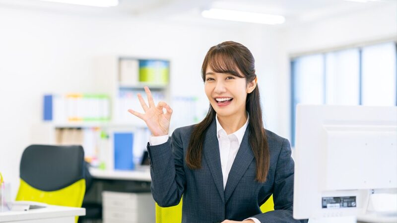 スーツの女性が右手でOKサインを作っている写真