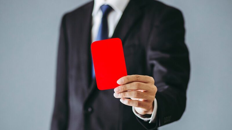 スーツの男性がレッドカードを出している写真