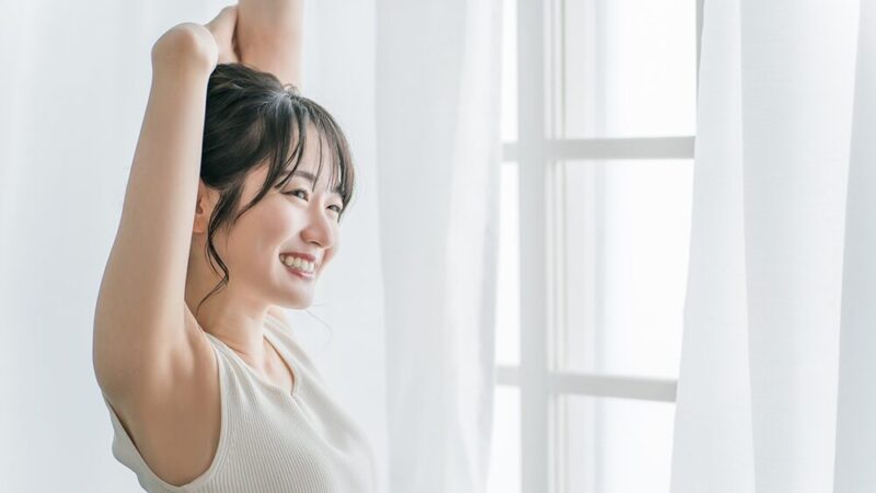 女性が笑顔で伸びをしている写真