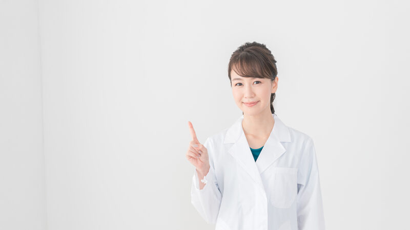白衣を着た女性が、、人差し指をたて説明している風景の写真