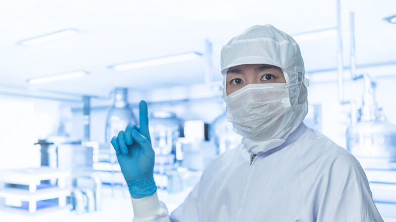 クリーンスーツを来た男性がチェックしている様子の写真