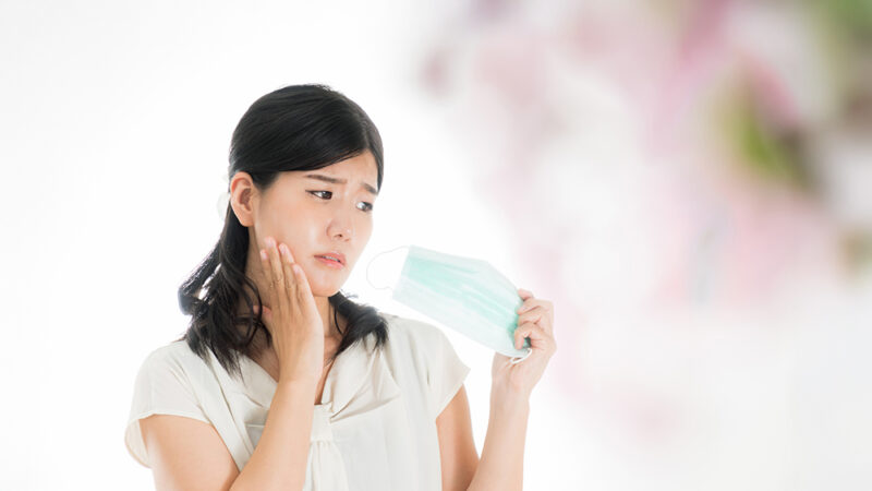 マスクをめんどくさそうに見ている女性の写真