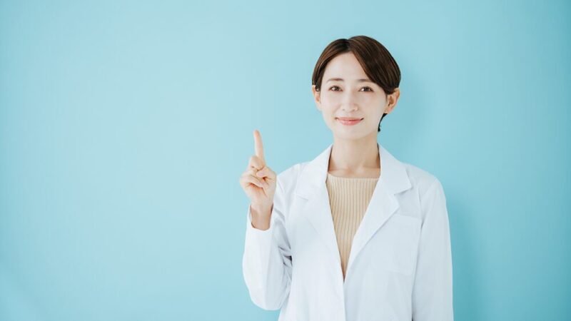 白衣の女性が一指し指をさしている写真