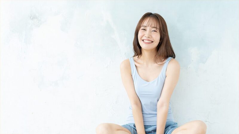 胡坐をかいた女性がリラックスした笑顔を見せている写真