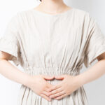 お腹を両手で抑えている女性の写真