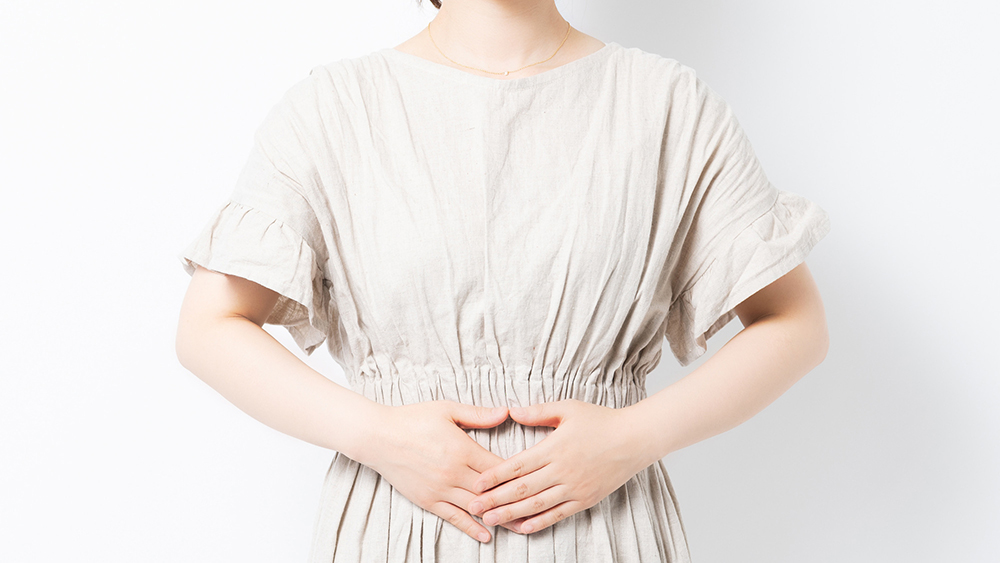 お腹を両手で抑えている女性の写真