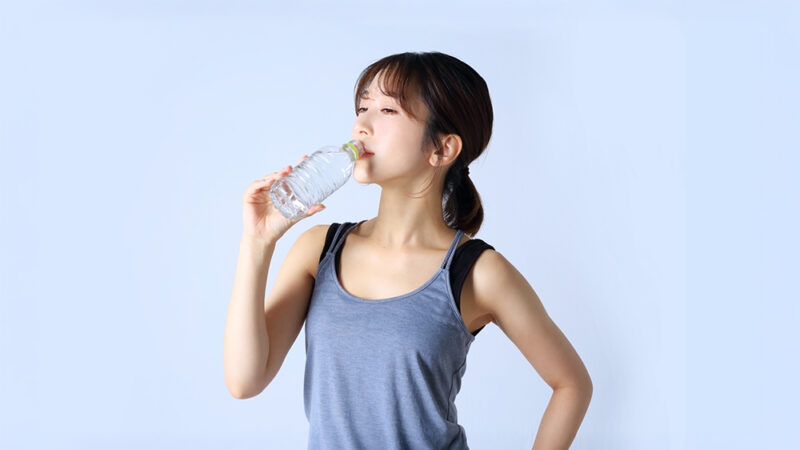 ペットボトルの水を飲んでいるスポーツウェアを着た女性の写真