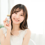 錠剤が入った瓶を手に持って微笑んでいる女性