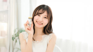 錠剤が入った瓶を手に持って微笑んでいる女性