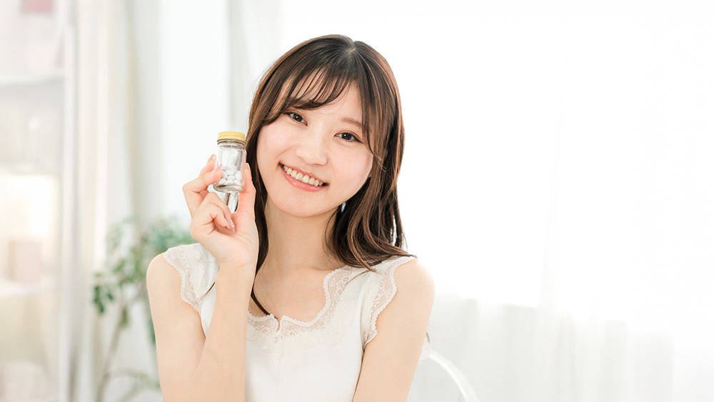 錠剤が入った瓶を手に持って微笑んでいる女性