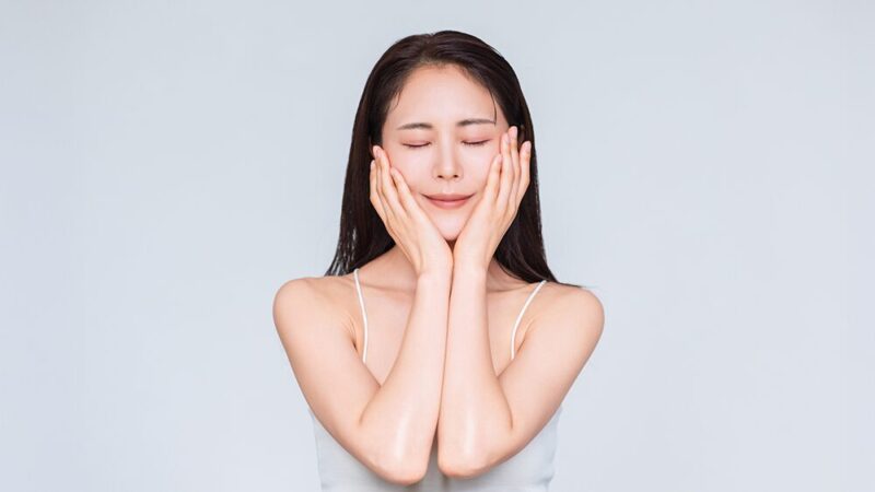 肌ツヤのいい女性が、目を閉じて頬に両手を当てている写真