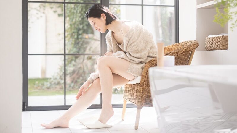 女性が前かがみで足に触れている写真