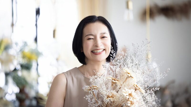 ミドル世代の女性が笑顔で花束を持っている写真