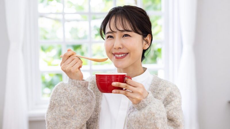 マグカップとスプーンを笑顔で持っている女性の写真