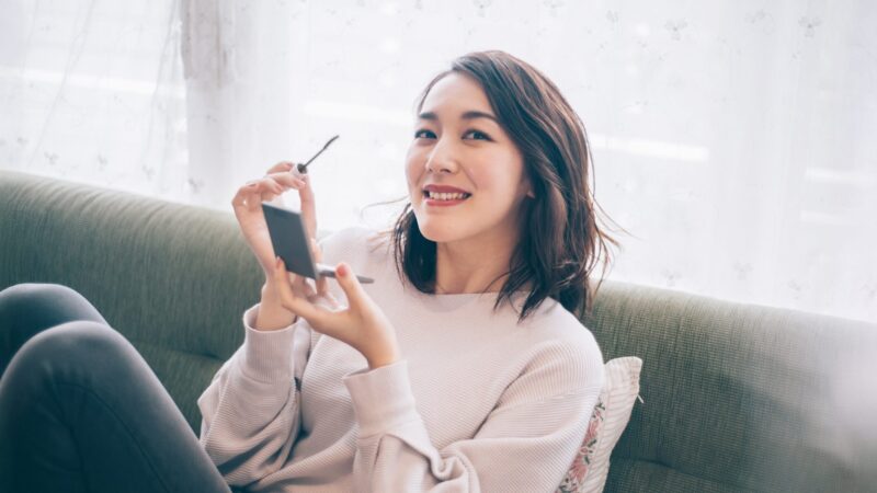 まつ毛ブラシを持った、笑顔の女性の写真