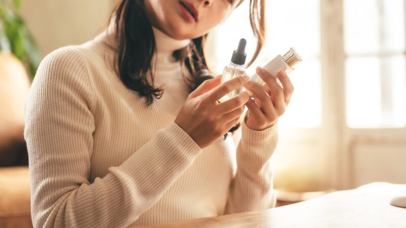 2つの化粧品ボトルを見比べて首をかしげている写真