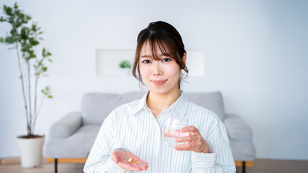 サプリメントをてのひらに乗せた笑顔の女性