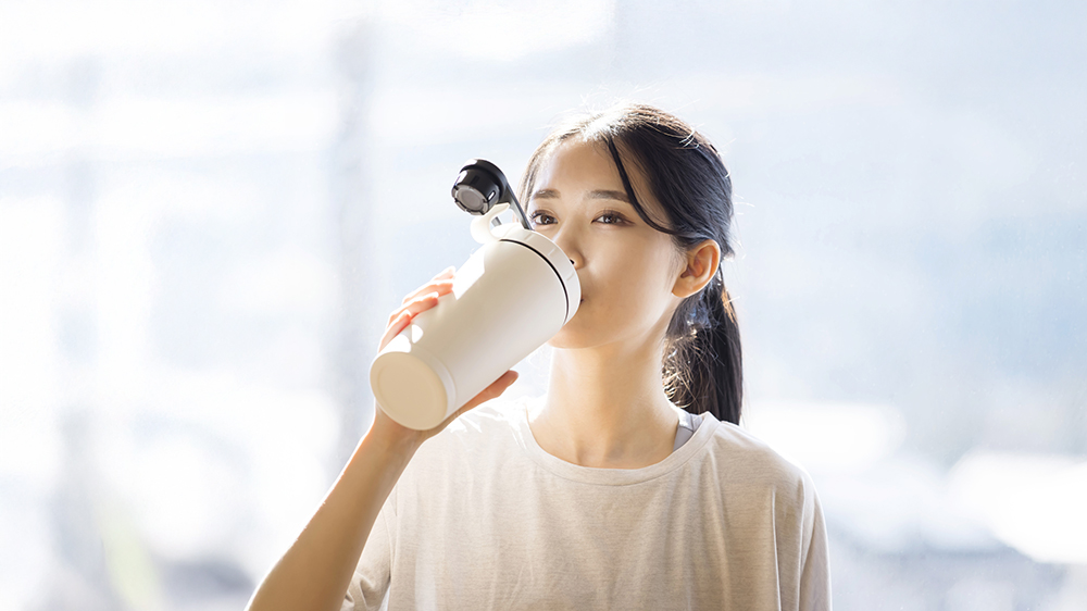 シェイカーに入ったプロテインをを飲む女性
