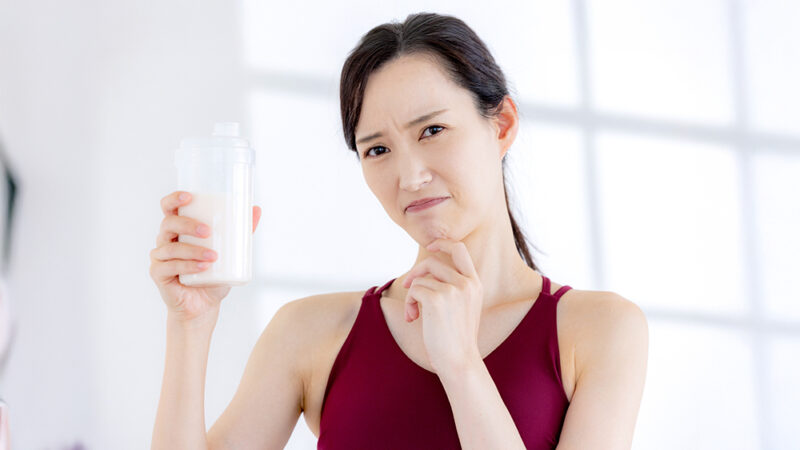 プロテインを手の持って悩んでいる女性