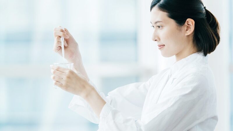 白衣の女性がスポイトとシリンジを持っている写真