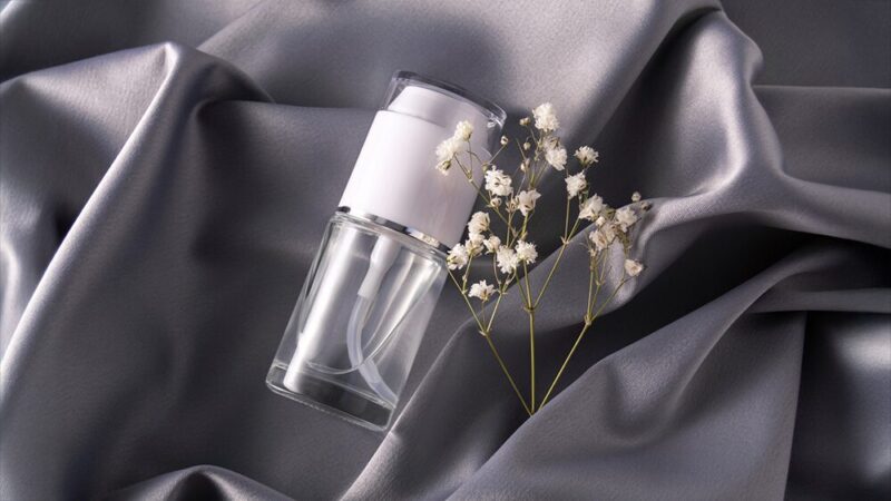 シルクの布の上に透明の化粧品と花の写真