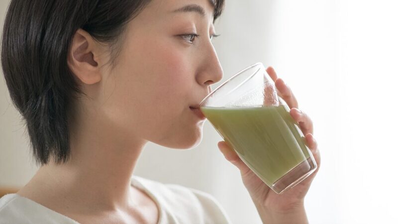 野菜ジュースを女性が飲んでいる写真