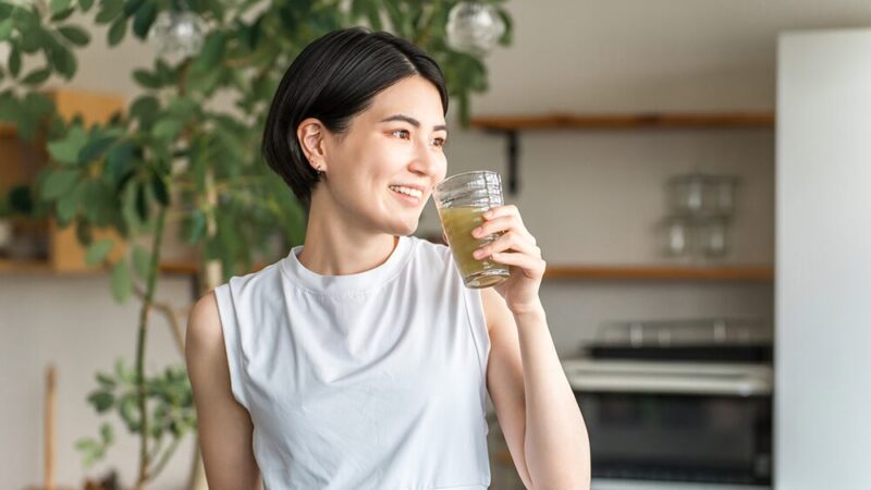 スポーティーな女性が緑の飲み物を飲んでいる写真