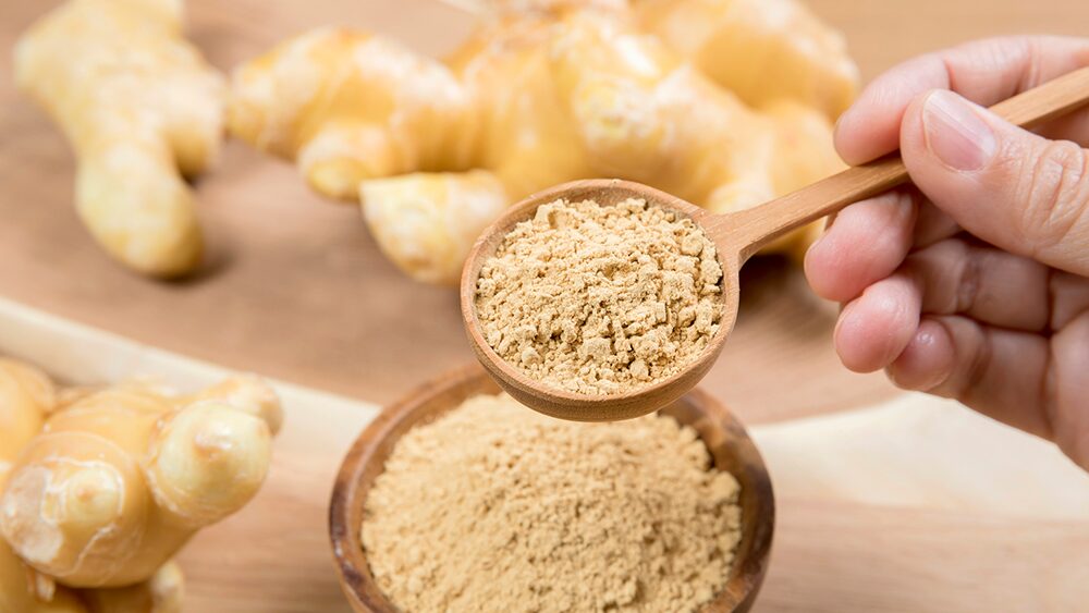 生姜とスプーンで茶色い粉末をすくっている写真