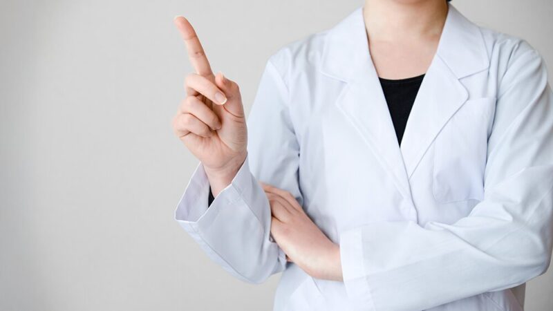 白衣の女性が人差し指を立てている写真