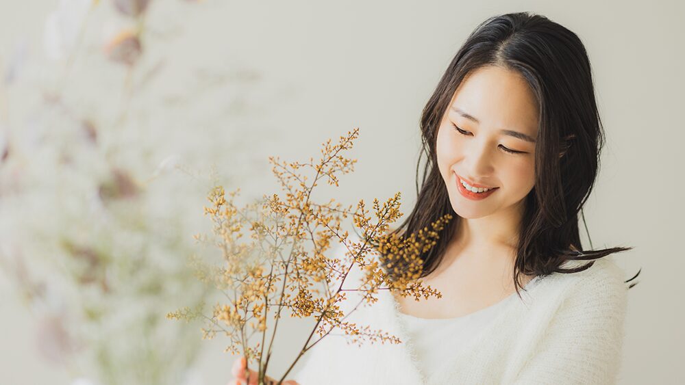 植物を笑顔で見つめている女性の写真