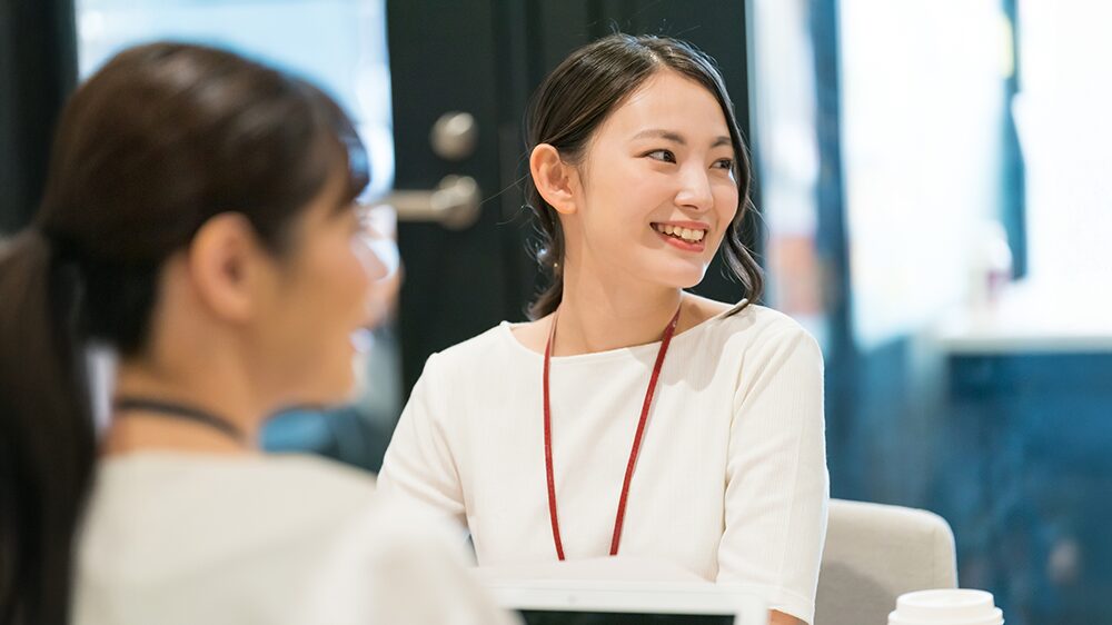 オフィスで女性二人が笑顔で談笑している写真